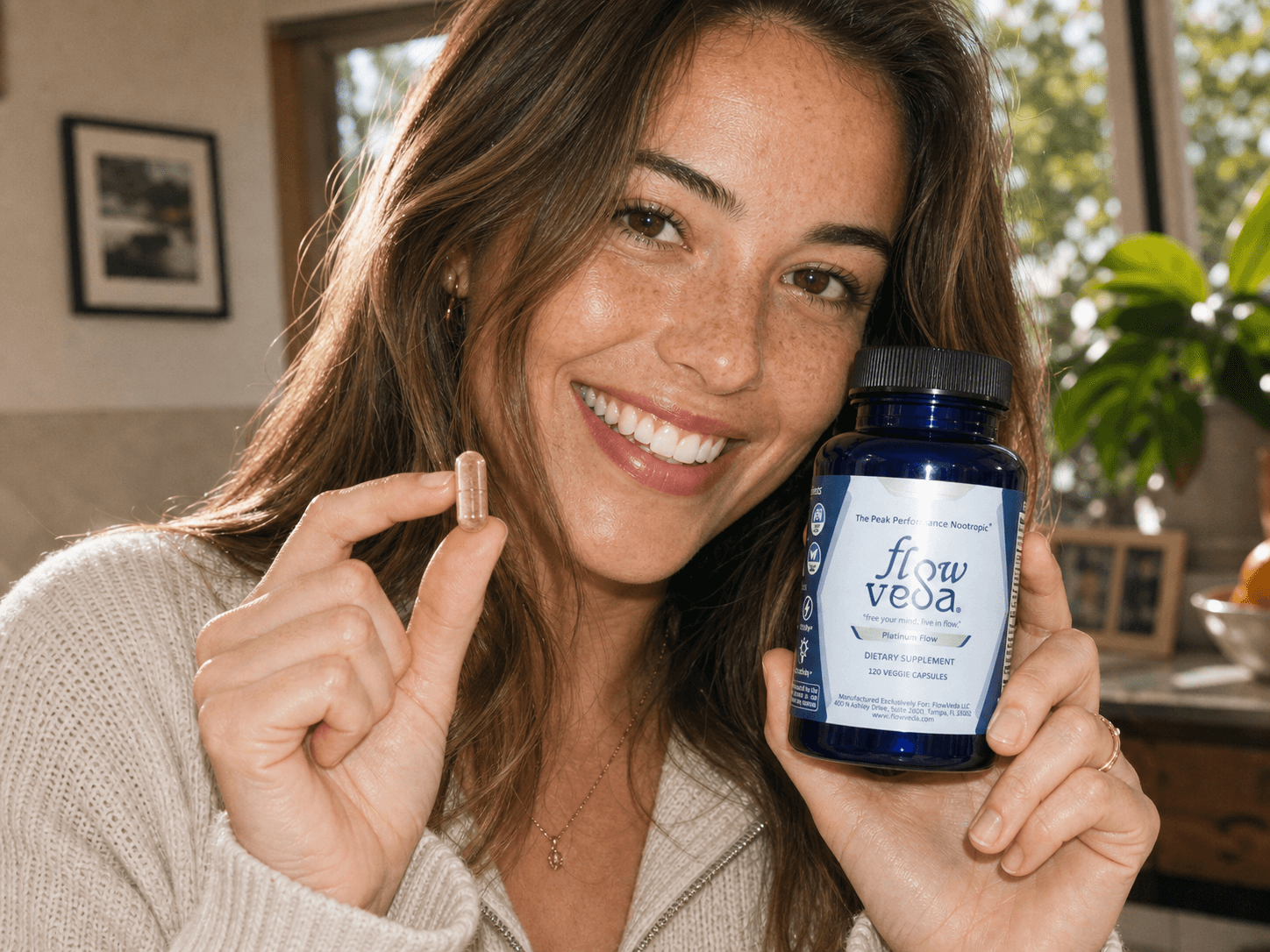 A woman holding a FlowVeda® capsule and bottle. The calm, focused attention to choose how she responds.