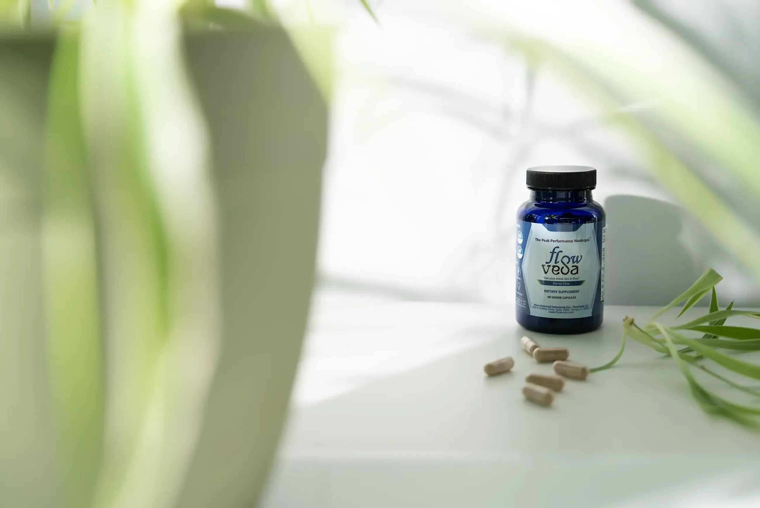 FlowVeda bottle on a sunlit table with soft greenery
